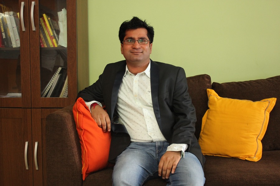 Layak Singh, seated in front of a bookcase, wearing a dark jacket over an open-collar shirt.